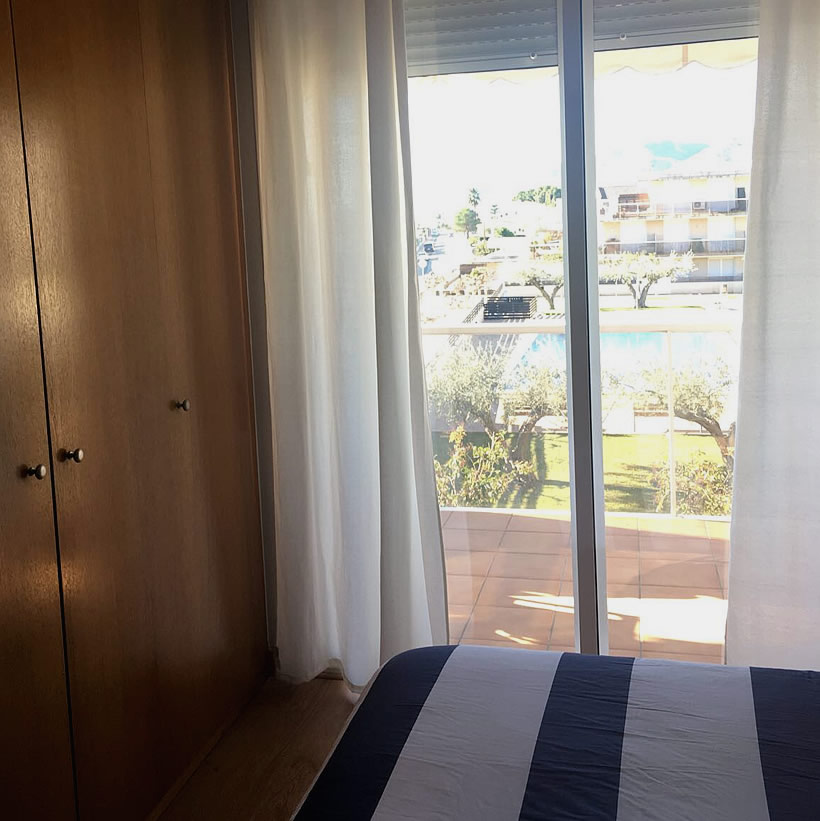 Grande chambre à coucher avec accès balcon et vue sur piscine et espaces verts, appartement résidentiel location Alcanar Playa